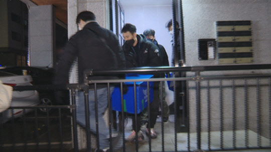 경찰이 지난 10일 오후 오스템임플란트 회삿돈 2215억 원을 횡령한 이모씨 가족의 주거지에서 압수수색을 마친 후 압수품을 옮기고 있다. <연합뉴스TV 캡처>